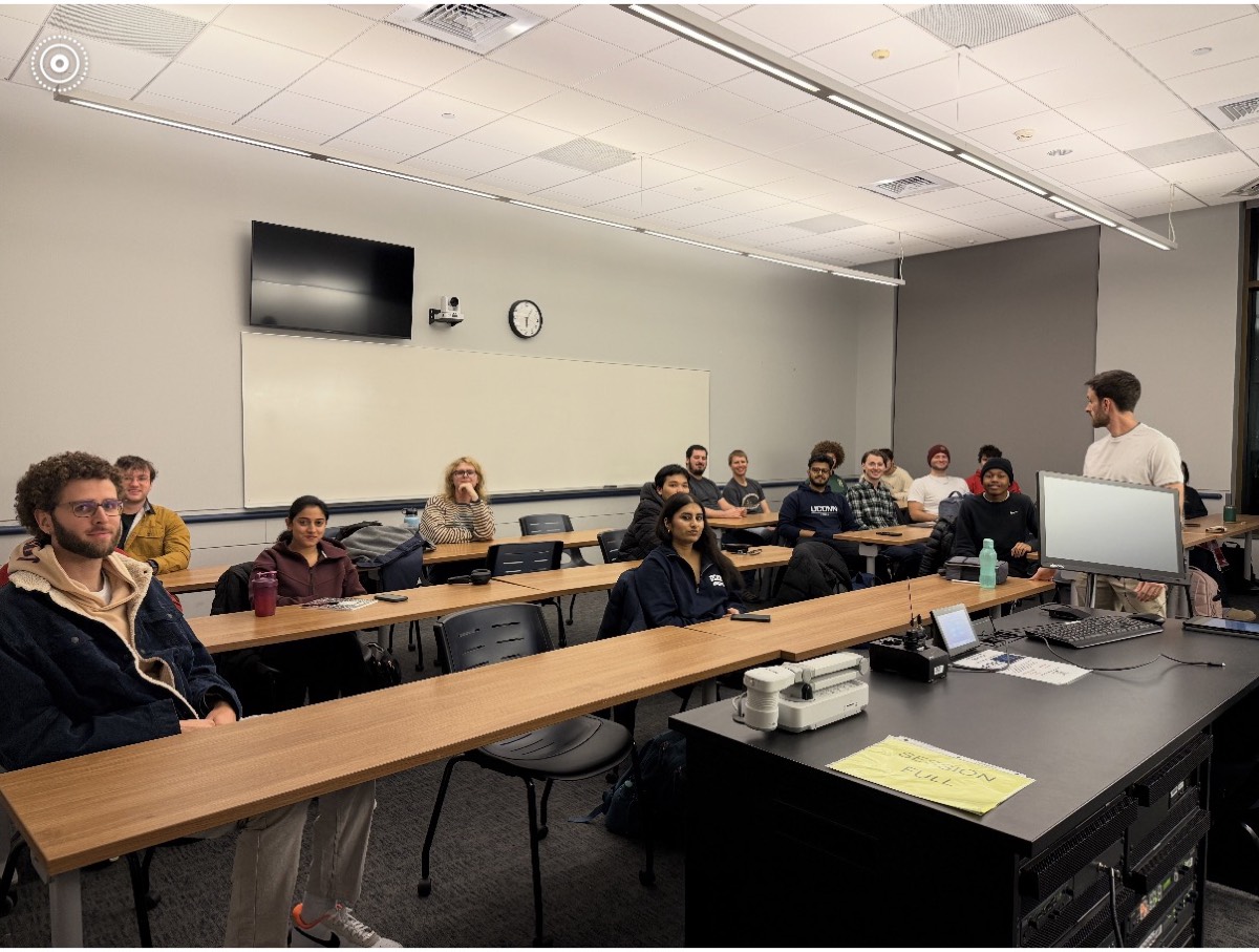 A club meeting in a UConn classroom, students at desks facing a presenter.